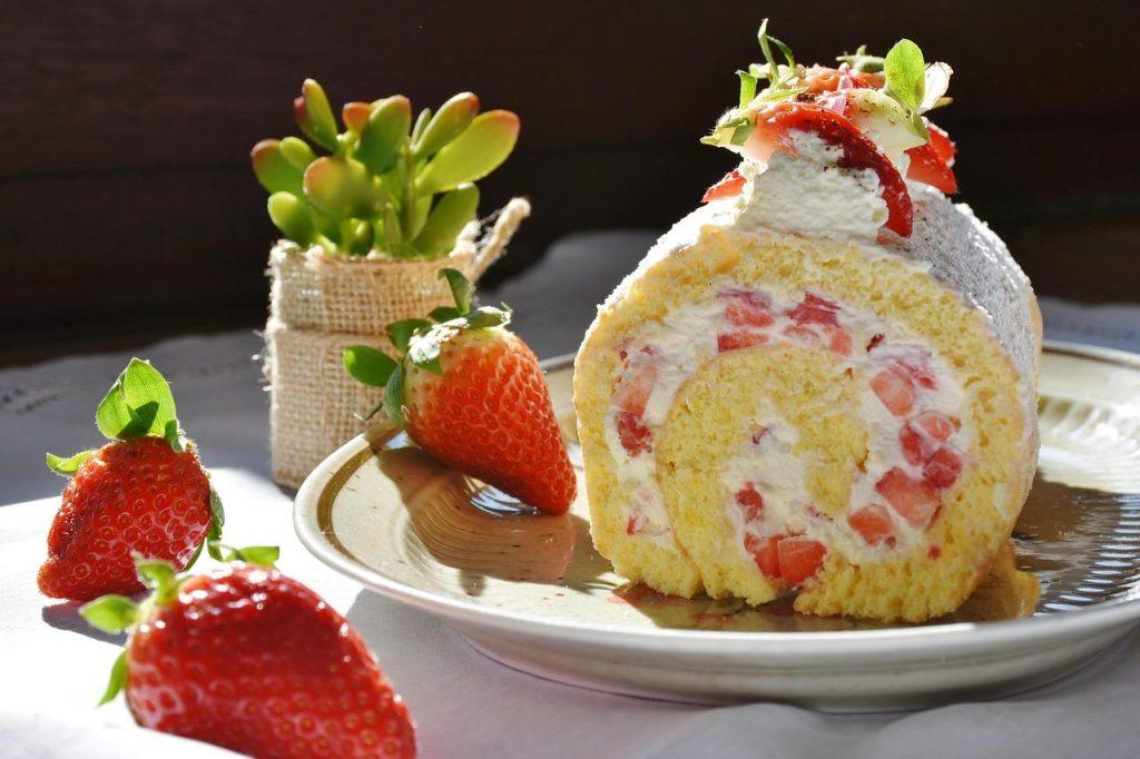 Strawberry cream roll cake slice filled with freeze dried strawberries and whipped cream on a plate